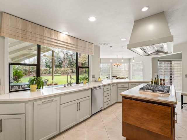 kitchen with extractor fan, light tile patterned floors, appliances with stainless steel finishes, a peninsula, and a sink