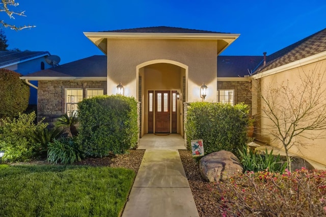 doorway to property with stone siding and stucco siding