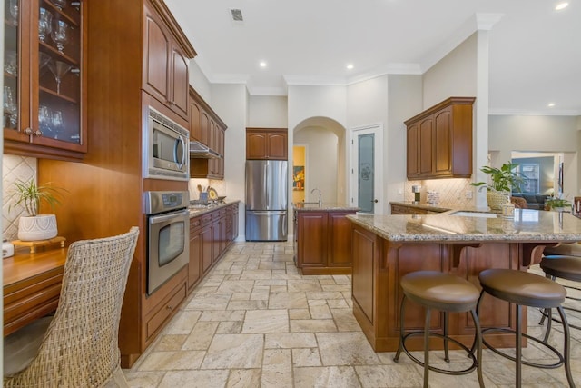 kitchen with visible vents, light stone counters, appliances with stainless steel finishes, a peninsula, and stone tile flooring