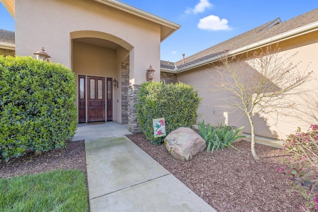 doorway to property featuring stone siding and stucco siding