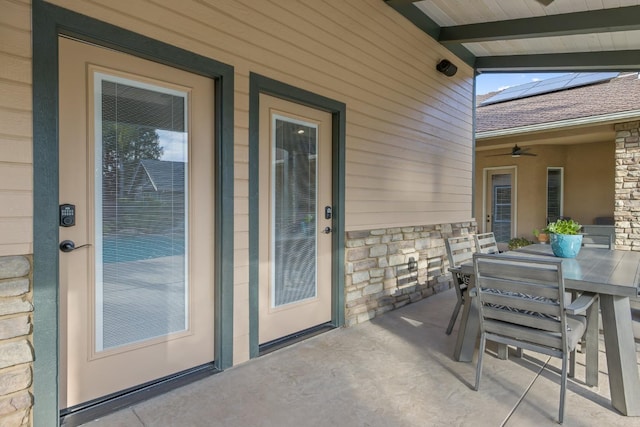 exterior space featuring outdoor dining space, a patio, stone siding, and solar panels