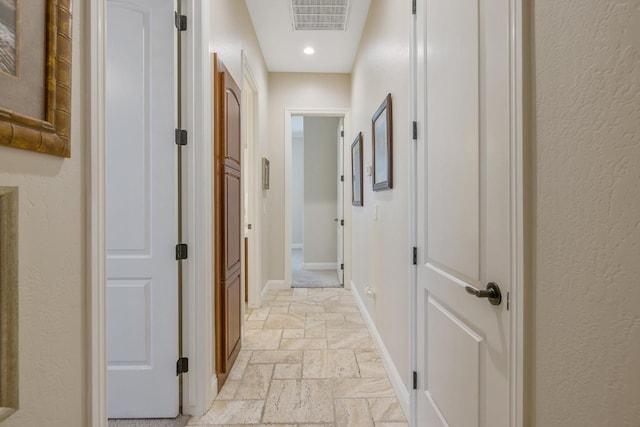 corridor with recessed lighting, visible vents, baseboards, and stone tile flooring