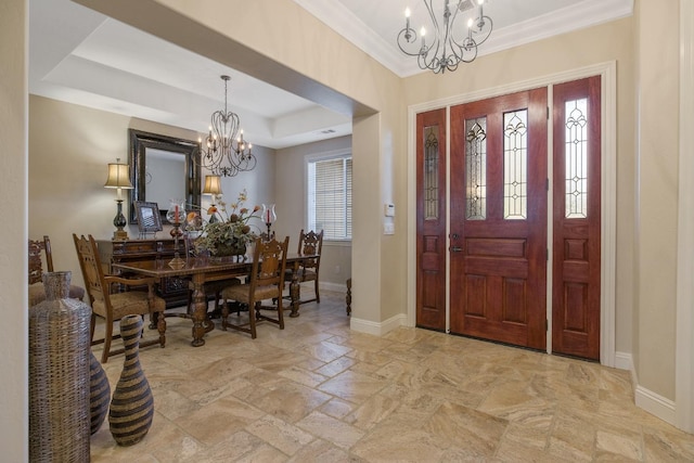 entryway featuring a tray ceiling, ornamental molding, baseboards, and a chandelier