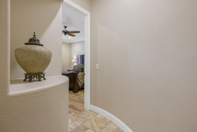 hallway with stone finish floor, crown molding, and baseboards