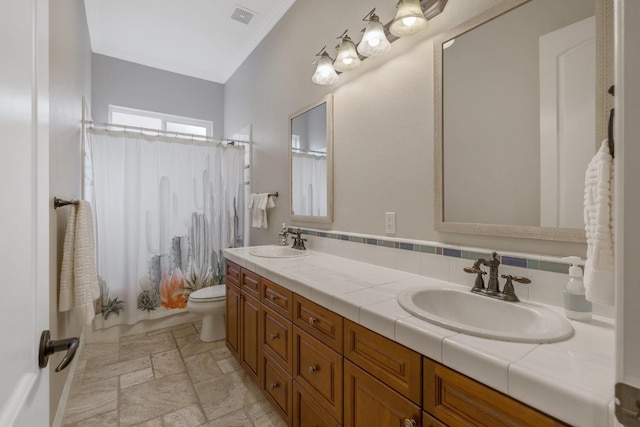 bathroom featuring stone tile flooring, double vanity, visible vents, and a sink