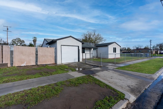 exterior space featuring concrete driveway, a gate, a garage, and a fenced front yard