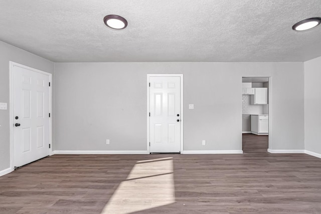 interior space featuring a textured ceiling, baseboards, and wood finished floors