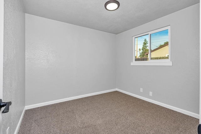 carpeted empty room featuring a textured ceiling and baseboards