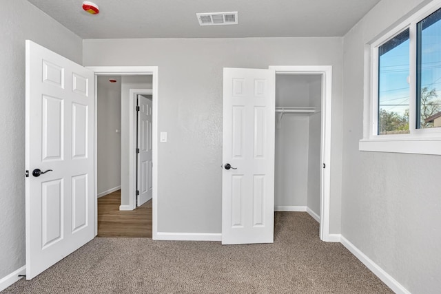 unfurnished bedroom with a closet, visible vents, baseboards, and carpet floors