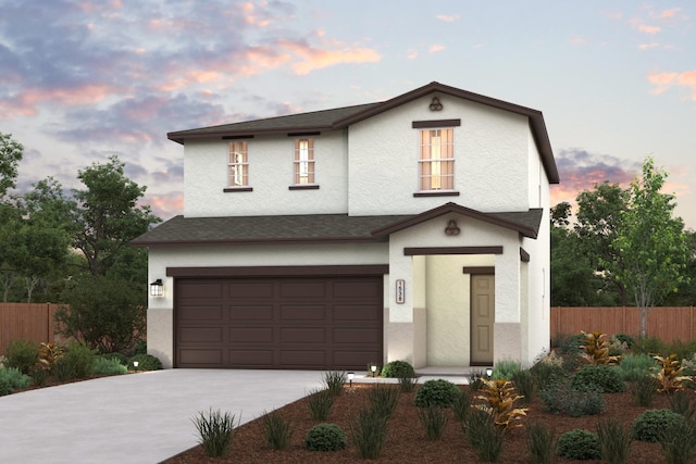 traditional home featuring fence, a garage, driveway, and stucco siding