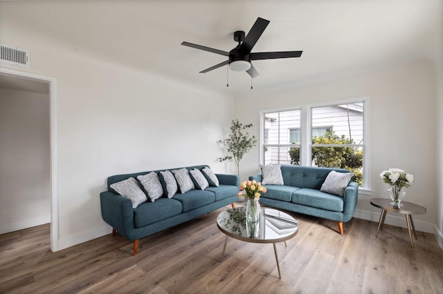 living area with a ceiling fan, wood finished floors, visible vents, and baseboards