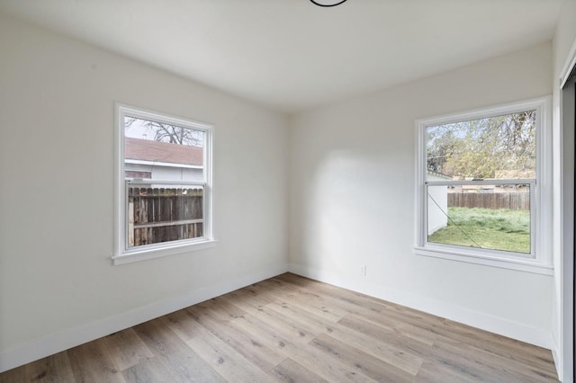 spare room with a wealth of natural light, baseboards, and light wood-style flooring