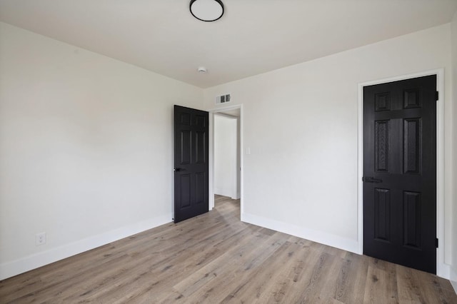 spare room with visible vents, baseboards, and wood finished floors