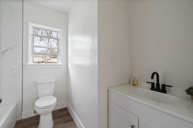 bathroom featuring toilet, vanity, baseboards, and wood finished floors