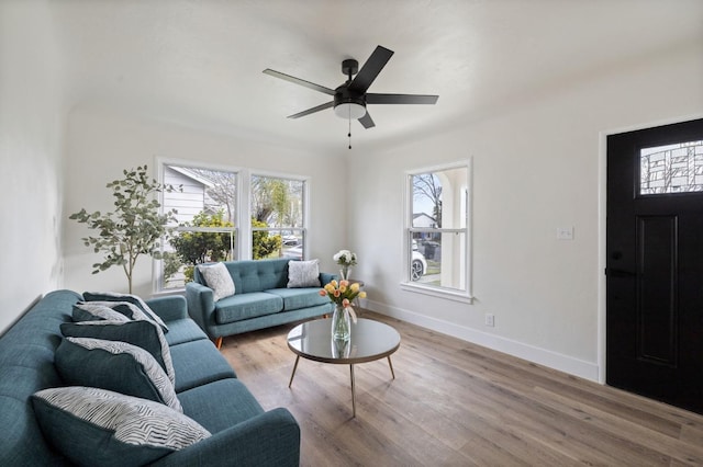 living room featuring wood finished floors, baseboards, and ceiling fan