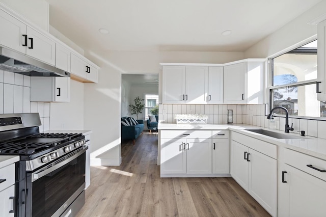 kitchen featuring tasteful backsplash, stainless steel range with gas stovetop, light countertops, and a sink