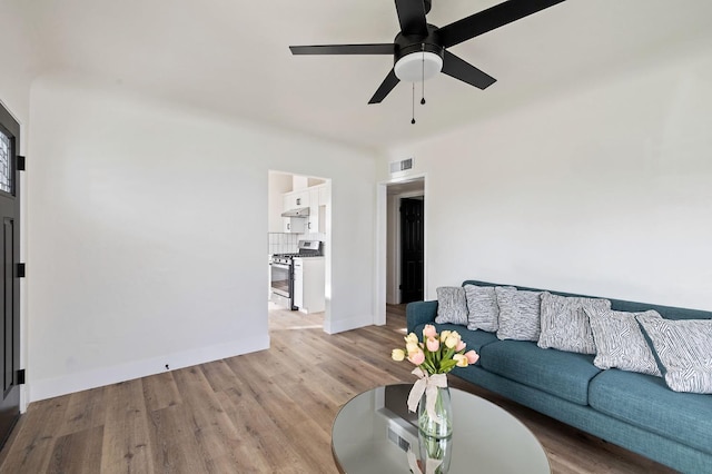 living room with visible vents, wood finished floors, baseboards, and ceiling fan