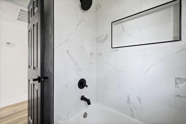 full bath featuring visible vents, tub / shower combination, baseboards, and wood finished floors