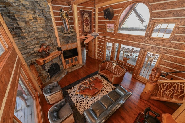 living area featuring a fireplace, a high ceiling, and wood finished floors