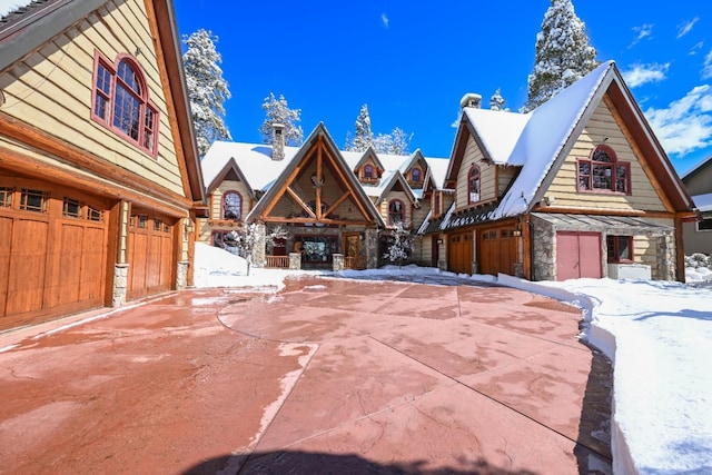 view of front facade with stone siding, driveway, a garage, and an outdoor fireplace