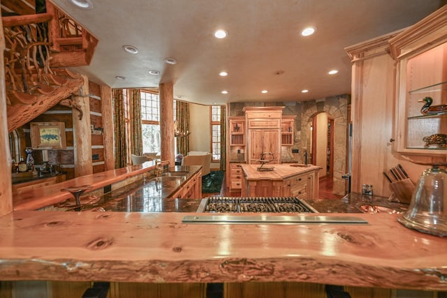 kitchen featuring open shelves, butcher block countertops, recessed lighting, arched walkways, and a sink