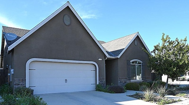 view of front facade with concrete driveway, roof with shingles, stucco siding, a garage, and stone siding