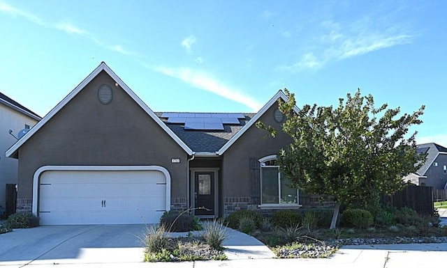 view of front of property with stucco siding, concrete driveway, a garage, stone siding, and roof mounted solar panels