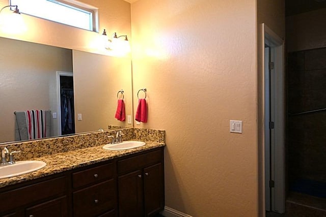 full bath with double vanity, baseboards, and a sink