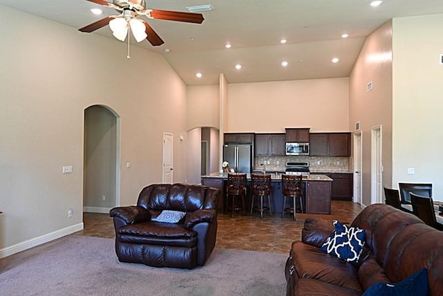 living area featuring visible vents, arched walkways, high vaulted ceiling, and ceiling fan