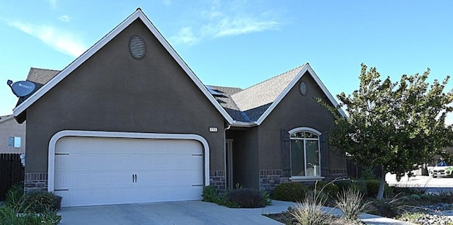 view of front of property featuring concrete driveway, a garage, stone siding, and stucco siding