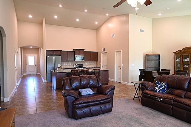 living area featuring arched walkways, visible vents, high vaulted ceiling, and ceiling fan