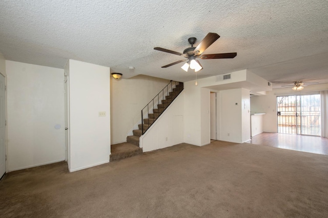 unfurnished living room with stairs, visible vents, carpet floors, and ceiling fan