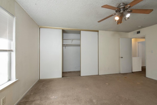 unfurnished bedroom with a ceiling fan, visible vents, a closet, a textured ceiling, and carpet flooring