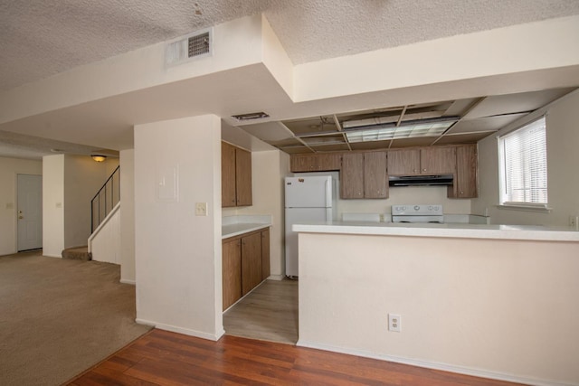 kitchen with visible vents, under cabinet range hood, light countertops, freestanding refrigerator, and range