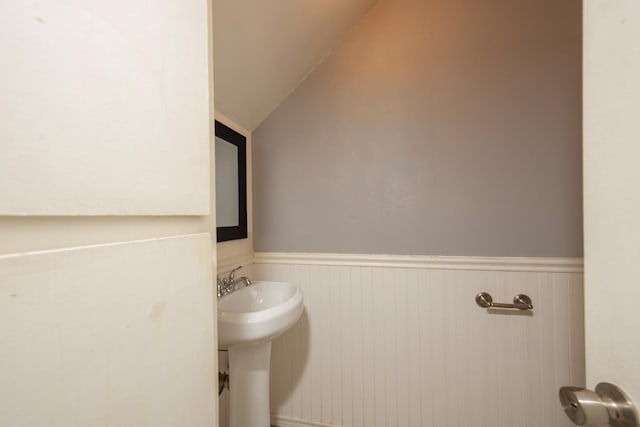 bathroom featuring a sink, wainscoting, and vaulted ceiling