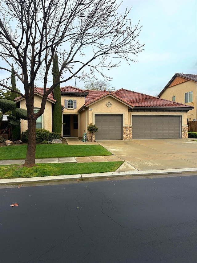 mediterranean / spanish-style home with driveway, an attached garage, stucco siding, stone siding, and a tiled roof