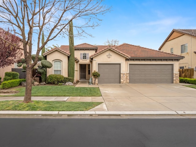 mediterranean / spanish house with fence, a tile roof, concrete driveway, stucco siding, and an attached garage