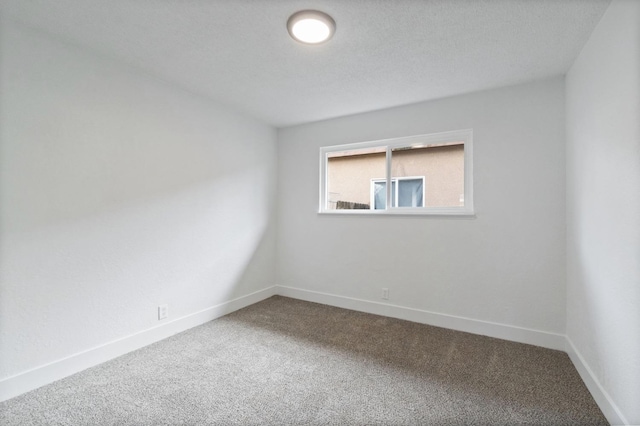 carpeted empty room featuring baseboards and a textured ceiling