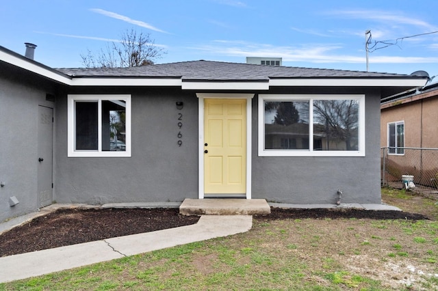 doorway to property featuring stucco siding and fence