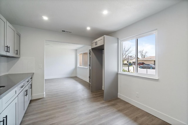 kitchen with baseboards, visible vents, light wood-type flooring, recessed lighting, and tasteful backsplash