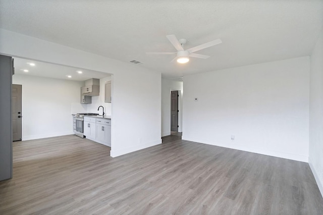 unfurnished living room featuring visible vents, baseboards, ceiling fan, and light wood finished floors