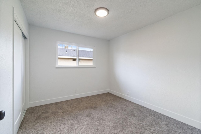 unfurnished bedroom with a closet, carpet floors, a textured ceiling, and baseboards