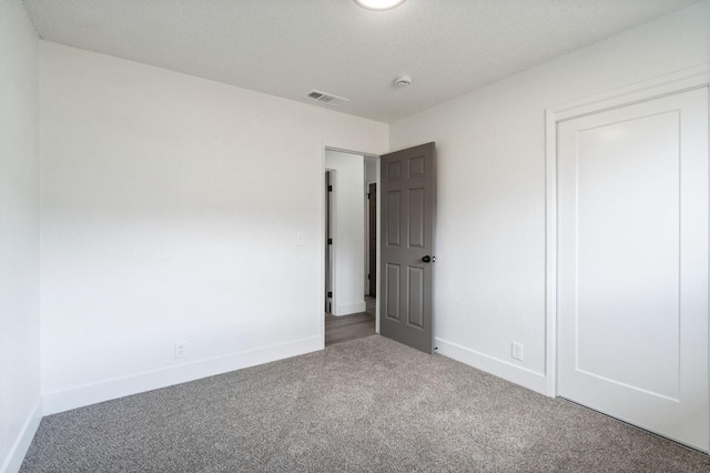 carpeted spare room featuring visible vents and baseboards