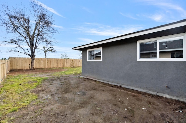 view of side of home featuring fence and stucco siding