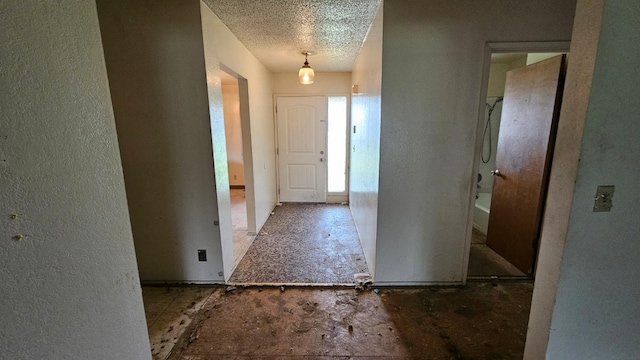 hall with a textured ceiling and a textured wall