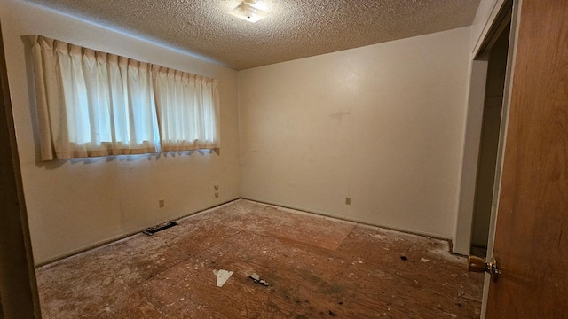 unfurnished room with a textured ceiling