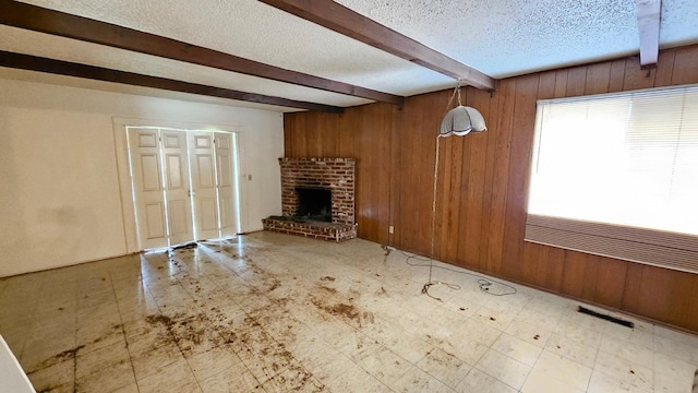 unfurnished living room with tile patterned floors, beamed ceiling, and wooden walls