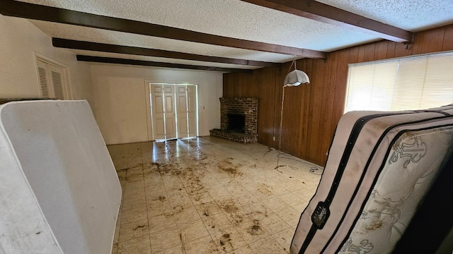 living room with beamed ceiling, a textured ceiling, wood walls, a fireplace, and light floors