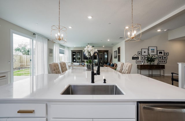 kitchen featuring a chandelier, open floor plan, stainless steel dishwasher, and a sink