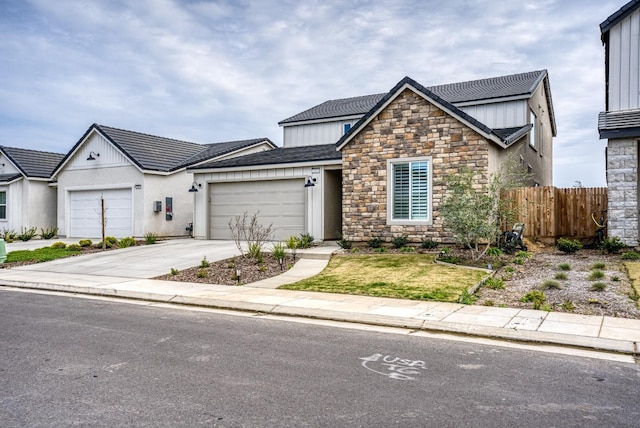 view of front of property featuring concrete driveway, a garage, fence, and stone siding